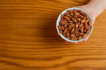 Hand holding white porcelain bowl with almonds