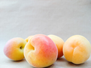 Close up apricots on beige background with copy space. Texture of yellow, orange, red ripe apricot fruits. Summer berries and fruits. Seasonal harvest.