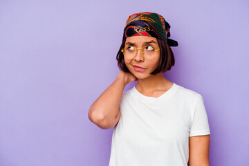 Young mixed race woman wearing a bandana isolated on purple background touching back of head, thinking and making a choice.