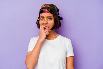 Young mixed race woman wearing a bandana isolated on purple background biting fingernails, nervous and very anxious.