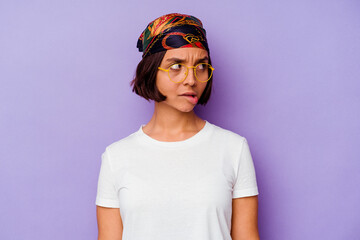 Young mixed race woman wearing a bandana isolated on purple background confused, feels doubtful and unsure.