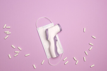 Non-contact infrared thermometer. Body Temperature Measurement Device. White capsule pills and...