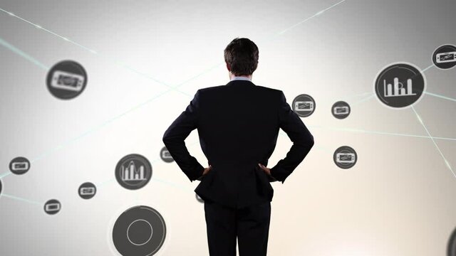 Animation of businessman looking at networks of connections with icons on grey background