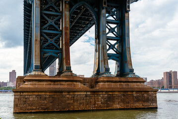 Detail of Pillar of Manhattan Bridge against cityscape of New York City. Steel Abutment With Bolt and Rivet Connections. Engineering and architecture