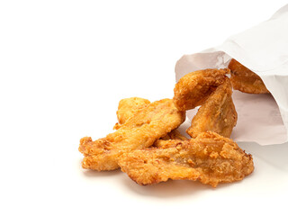 Fried bananas pouring outside of a paper bag placed on white background. Snack unhealthy concept