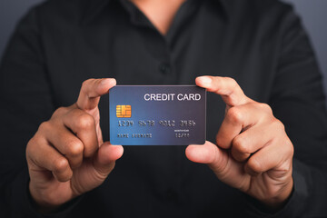 Businessman holding a mockup blue credit card while standing in a studio with copy space for text. Close-up photo. Money and business concept