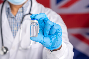A doctor holding a vaccine bottle against the background of the United Kingdom flag. Vaccine for immunization and treatment from virus infection. Concept of medical and the fight against the virus