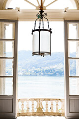 View from the balcony and from the window from an old villa on Lake Como in Italy. Antique forged lamp with a large shade.