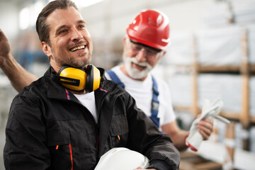 Portrait of workers in factory. Colleagues with helmet working in factory..