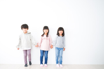 Fototapeta premium 壁に並ぶ3人の子どもたち