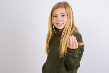 Caucasian kid girl wearing green knitted sweater against white wall inviting to come with hand....