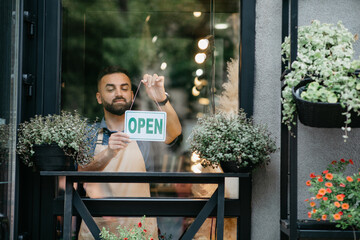 Business concept, caucasian man holding open sign indoors in shop