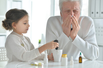 Granddaughter giving medicine to her grandfather in room