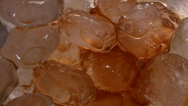 Black coffee is poured into a glass filled with ice cubes to create a refreshing coffee drink. Iced coffee, frappe, frappe coffee, frappuccino. Slow motion. Close up.
