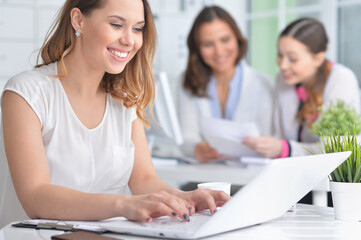young women sit at the table and work in a modern office