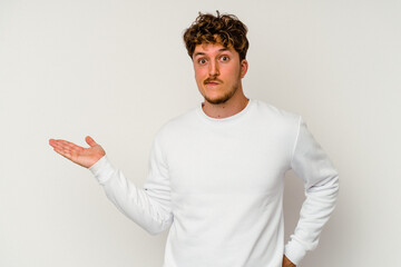 Young caucasian man isolated on white background doubting and shrugging shoulders in questioning...