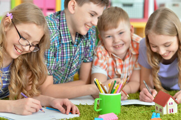 Fototapeta premium Children lying on floor drawing with pencils