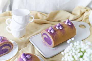 Obraz na płótnie Canvas Swiss Roll Cake with sweet purple potato filling set on cafe table.