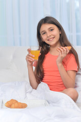 Obraz na płótnie Canvas Cute girl with breakfast at home on bed