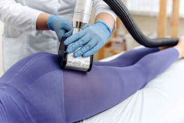 Fototapeta premium LPG, and body contouring treatment in clinic. Beautiful woman getting beauty therapy against cellulite with LPG machine on her buttocks