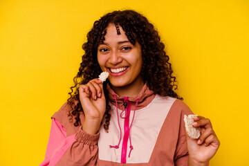 Young mixed race sport woman eating a rice cakes isolated on yellow background