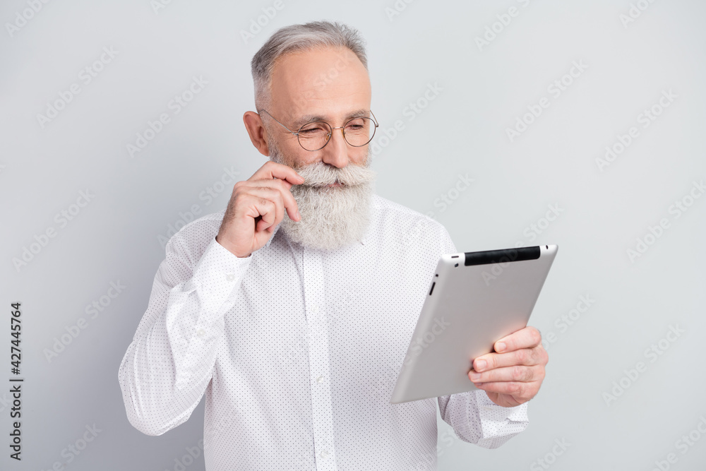 Sticker photo of attractive focused happy old man look hold tablet touch mustache isolated on grey color bac