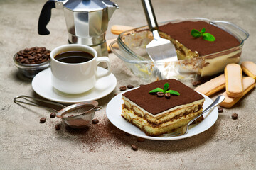 Traditional Italian Tiramisu dessert in glass baking dish and portion on grey concrete background