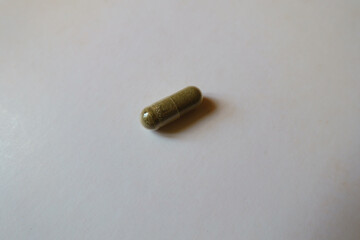 Close view of one greenish brown capsule of iron bisglycinate