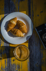 Still life with retro camera and cup of coffee on the wooden background. Sweets on the plate on the wooden background