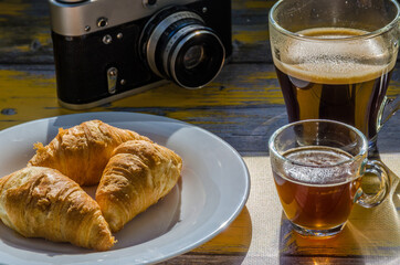 Still life with retro camera and cup of coffee on the wooden background. Sweets on the plate on the wooden background