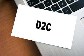 White sticky note reminder on laptop keyboard with D2C word. Paper note on computer background