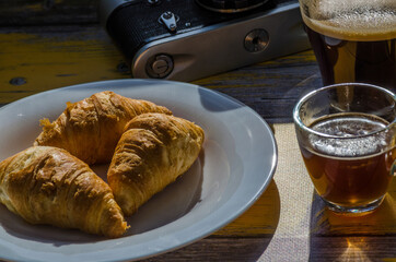 Still life with retro camera and cup of coffee on the wooden background. Sweets on the plate on the wooden background