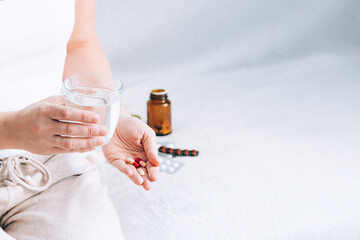 A woman is holding a glass of water and medicine pills. Health and medicine.