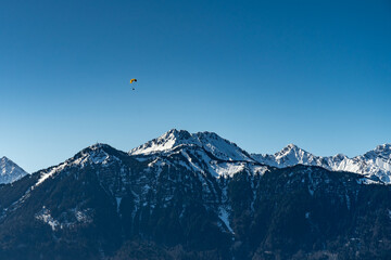 Paragleiter über dem Walgau, Para glider over the valley of Ill, with the mountains from Brand in the background. Zimba und Mondspitze, verschneite Berge im Hintergrund