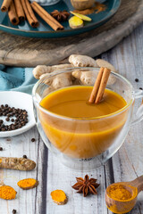 Close up of a tea cup filled with golden milk and a cinnamon stir stick.
