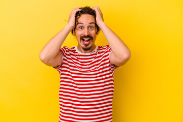 Young caucasian man isolated on yellow background screaming, very excited, passionate, satisfied with something.