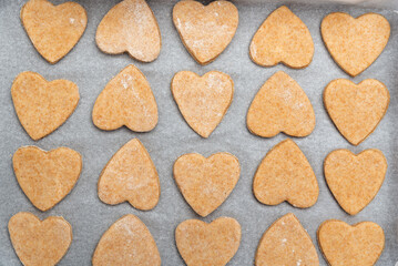 Heart shaped shortbread cookies on parchment paper. Whole grain baked goods. Top view