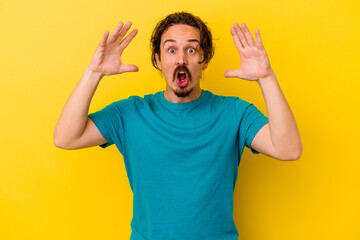 Fototapeta premium Young caucasian man isolated on yellow background celebrating a victory or success, he is surprised and shocked.