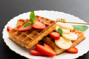 Belgium waffles with strawberry and banana with mint on plate