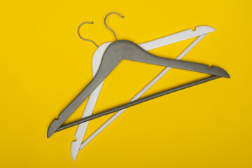 White and gray wooden hangers on yellow background, top view. Wardrobe concept