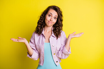 Portrait of lovely clueless wavy-haired girl shrugging shoulders isolated over bright yellow color...