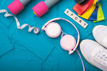 Fototapeta na wymiar sport at home - white sneakers, dumbbells and rubber bands, headphones and measurement tape