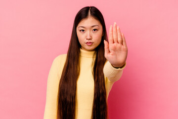 Young chinese woman isolated on pink background standing with outstretched hand showing stop sign,...