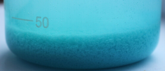 Blue precipitate of copper carbonate precipitated at the bottom of a beaker.
