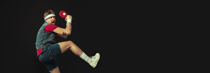 Young Caucasian funny man playing ping pong isolated on black background.