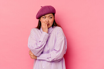 Young chinese woman isolated on pink background biting fingernails, nervous and very anxious.