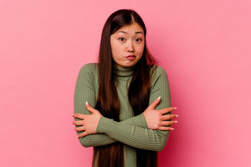 Young chinese woman isolated on pink background shrugs shoulders and open eyes confused.