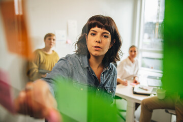 Woman discussing new ideas with team using sticky notes