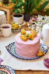 Pumpkin sponge cake with berry cream, decorated with physalis. Side view. 