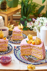 Pumpkin sponge cake with berry cream, decorated with physalis. Side view. 